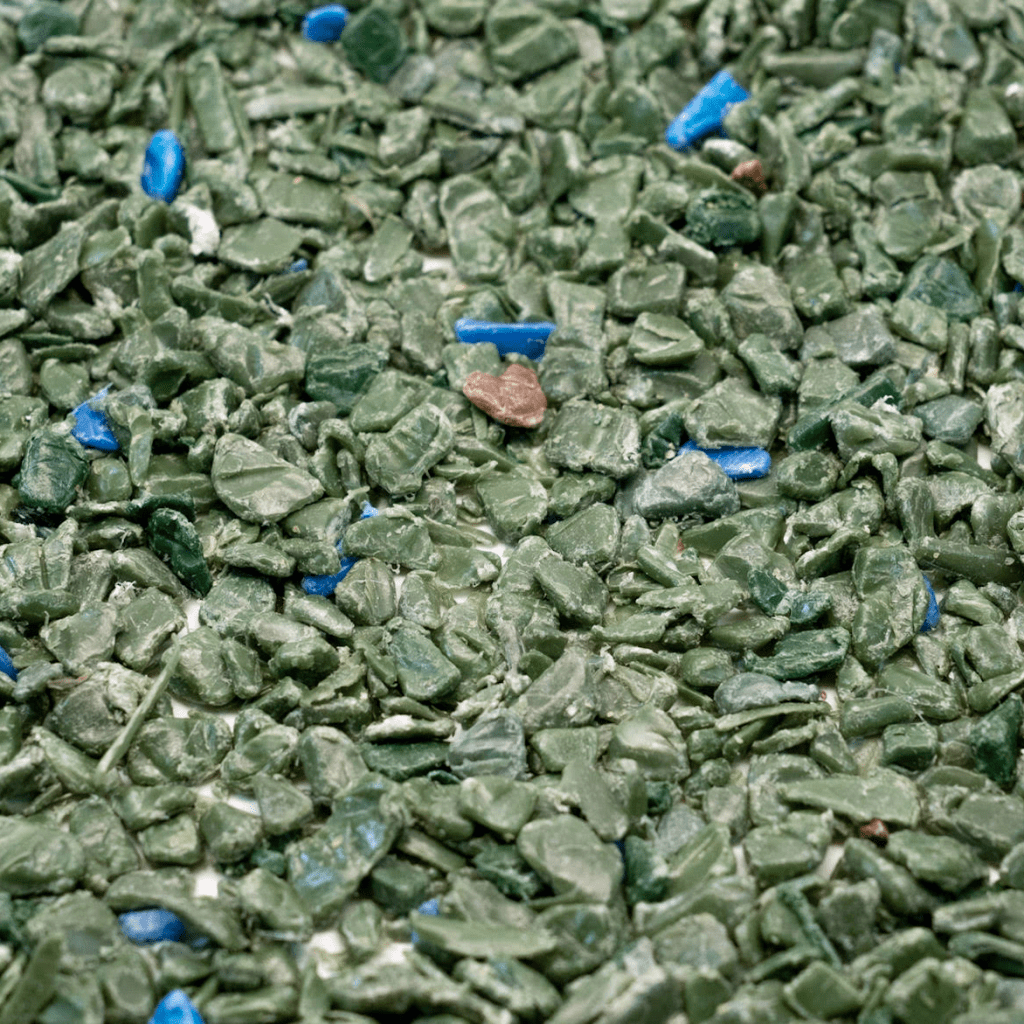 Close-up of recycled PP pellets in green, with a few blue and brown PP pellet colours mixed in.