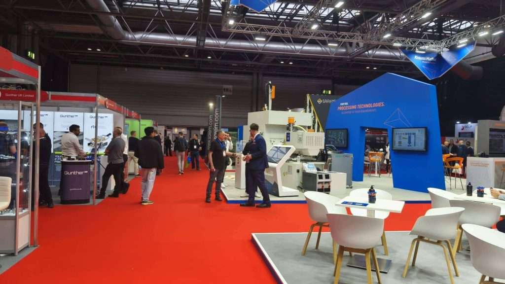 People networking at Interplas 2026, a plastics industry event at the NEC with stands and displays.